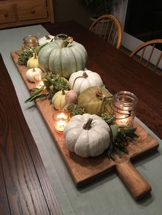 a wooden table topped with white pumpkins and candles