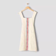 a white dress with red, blue and green stripes hanging on a wooden hanger