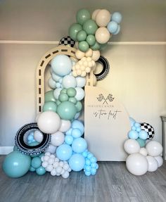 the balloon arch is decorated with blue, white and green balloons