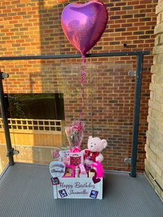 two teddy bears and a heart shaped balloon are on the porch with a birthday card