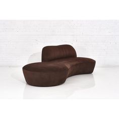 a large brown couch sitting on top of a white floor next to a brick wall