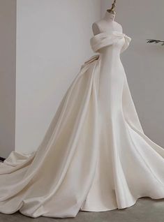 a white wedding dress on display in a room with an open back and long train