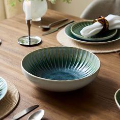 a wooden table topped with plates and bowls