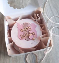 a pink birthday cake in a box on a table