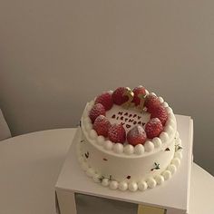 a white cake topped with strawberries on top of a table next to a box