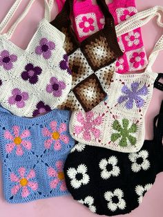 four crocheted purses are on a pink surface and one is black, the other is white