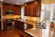 a large kitchen with wooden cabinets and stainless steel appliances in the center, along with marble counter tops