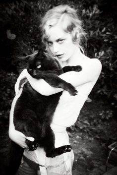 a woman holding a black cat in her arms