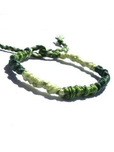 two green and white bracelets on a white surface with one beaded in to the middle