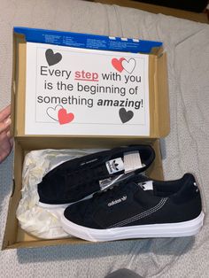 a pair of black shoes sitting in a box on top of a bed with a sign that says every step with you is the beginning of something amazing