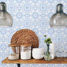 a shelf with jars, bowls and vases on it in front of a tiled wall