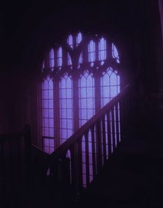 the stairs lead up to an arched window in a dark room with light coming through