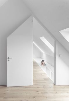 an attic bedroom with white walls and wood flooring is seen from the doorway to the loft