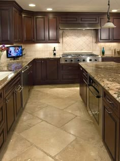 a large kitchen with marble counter tops and wooden cabinetry, along with stainless steel appliances