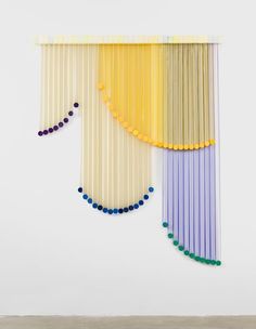 an art piece with different colored sticks hanging from it's sides and beads on the side