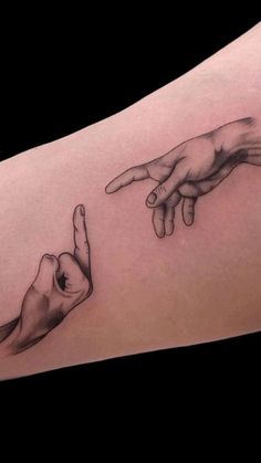 two hands pointing at each other in front of the same person's arm tattoo