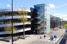 some people are walking down the street in front of a large building with many windows