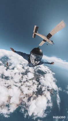 a man flying through the air while wearing a skydiver helmet and holding his arms out