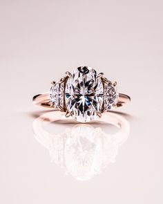 an engagement ring with three stone diamonds on the band and side stones set in 18k rose gold