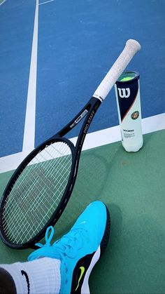 a tennis racquet sitting on the ground next to a can