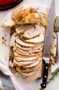 sliced turkey on a white plate with a knife and fork next to the whole turkey