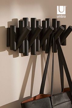 a black purse hanging on the wall next to a coat rack with several poles attached