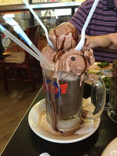 a man sitting at a table in front of a cup filled with ice cream and chocolate