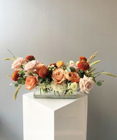 an arrangement of flowers in a vase on a white pedestal