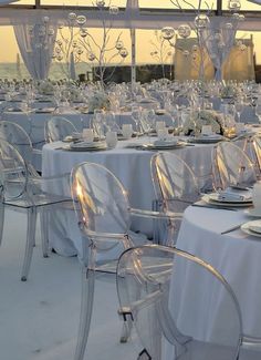 tables and chairs are set up for an outdoor event with white linens on them