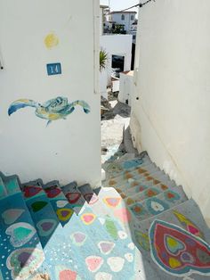 an alleyway with colorful rugs and artwork on the ground in front of it