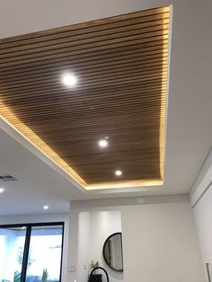 a living room with white walls and wood ceilinging, along with a round mirror on the wall