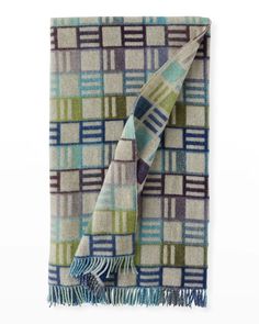 a blanket with blue, green and white squares on the bottom is folded in two rows