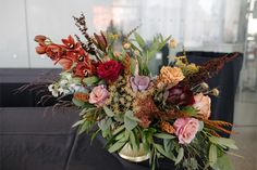 a vase filled with lots of flowers on top of a black tablecloth covered table