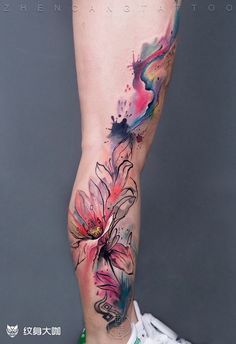 a woman's leg with colorful watercolor tattoos on her legs and flowers painted on the side