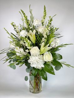 a vase filled with white flowers and greenery