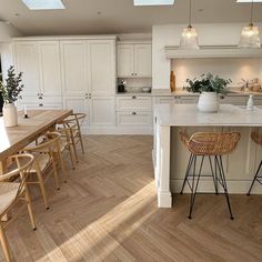 a kitchen with white cabinets and an island in the middle, surrounded by wooden flooring