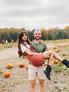 a man carrying a woman on his back in a pumpkin patch