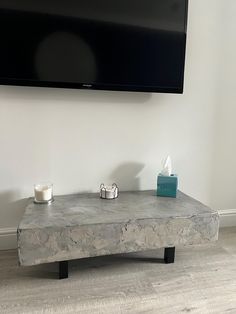 a flat screen tv mounted on the wall above a stone coffee table