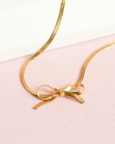 A dainty herringbone necklace with a bow! This necklace is adjustable to length as a choker. Materials: ﻿﻿This necklace is gold plated and is recommended to be taken off in the water or when working out. Final Sale: This item is final sale and not eligible for returns. Please double check your wrist size and any details prior to ordering. xo - We appreciate your understanding! Chic Delicate Chain Herringbone Necklace As Gift, Chic Herringbone Necklace With Delicate Chain For Gift, Chic Herringbone Necklace With Delicate Chain As Gift, Chic Snake Chain Choker As A Gift, Herringbone Choker Necklace For Gift, Gift Herringbone Choker Necklace, Elegant Herringbone Choker Necklace As Gift, Gold Herringbone Choker Necklace As Gift, Gold Herringbone Choker Necklace For Gift