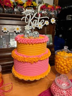 a three tiered cake sitting on top of a table next to candy and candies