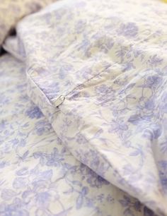 an unmade bed with blue and white floral bedspread on top of it