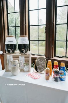 two wine glasses sitting on top of a white table next to bottles and other items