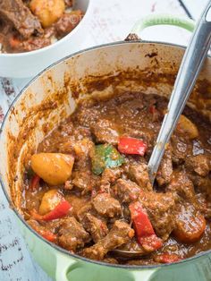 a pot full of stew with two spoons in it and another bowl on the side