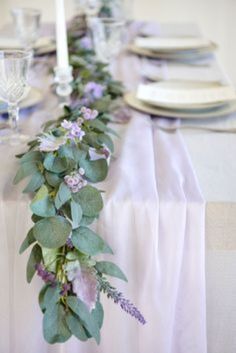 the table is set with purple flowers and greenery