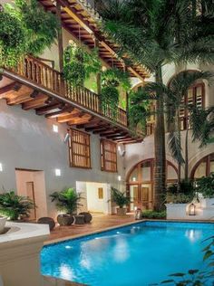 an indoor swimming pool surrounded by greenery and wooden balconies with lights on