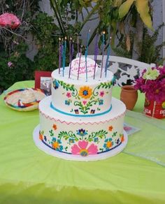 a decorated cake sitting on top of a table next to potted plants and flowers