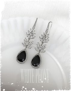 black and white photo of earrings with crystal accents on plate in front of white background