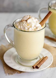 two mugs filled with hot chocolate and cinnamon on top of a white saucer