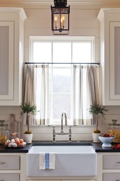 a kitchen with white cabinets and black counter tops, an open window above the sink