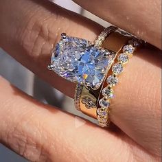 a woman's hand with two rings on it and a blue diamond in the middle